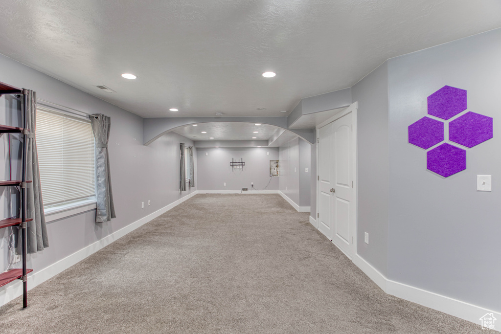 Basement featuring arched walkways, carpet, baseboards, and recessed lighting