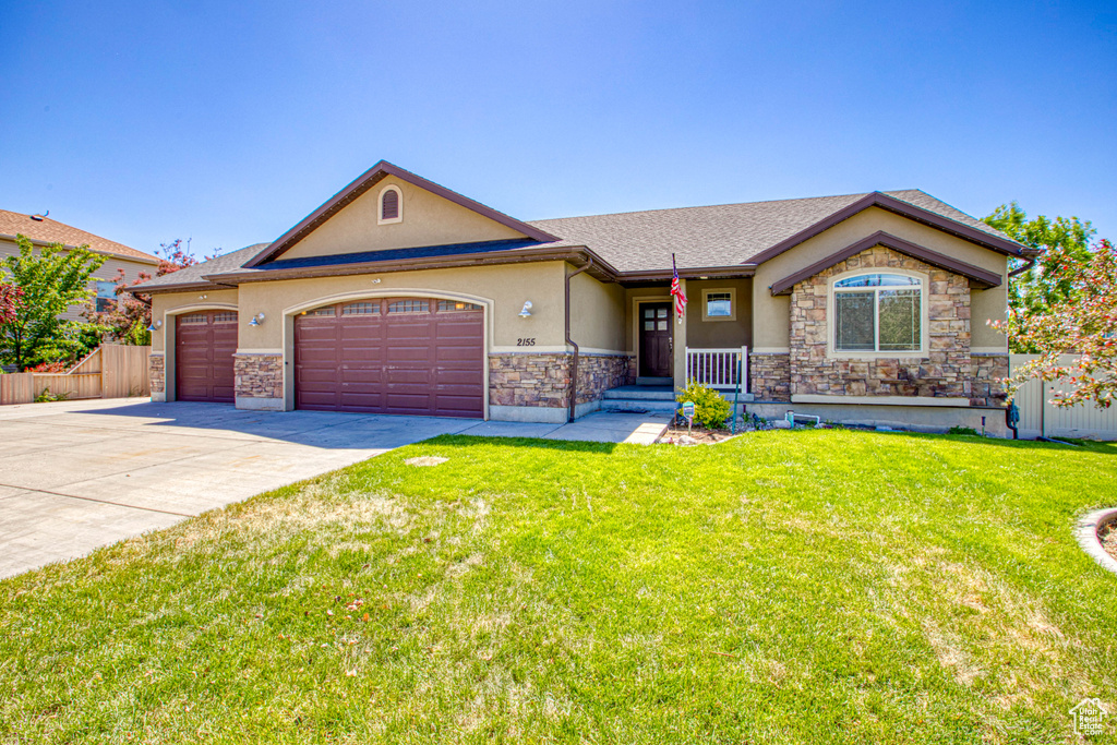 View of front facade with stucco siding, a garage, concrete driveway, stone siding, and roof with shingles