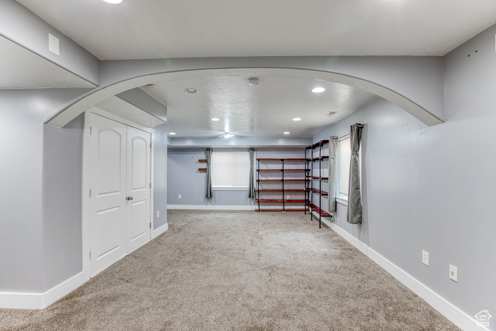 Basement with carpet floors, recessed lighting, arched walkways, and baseboards