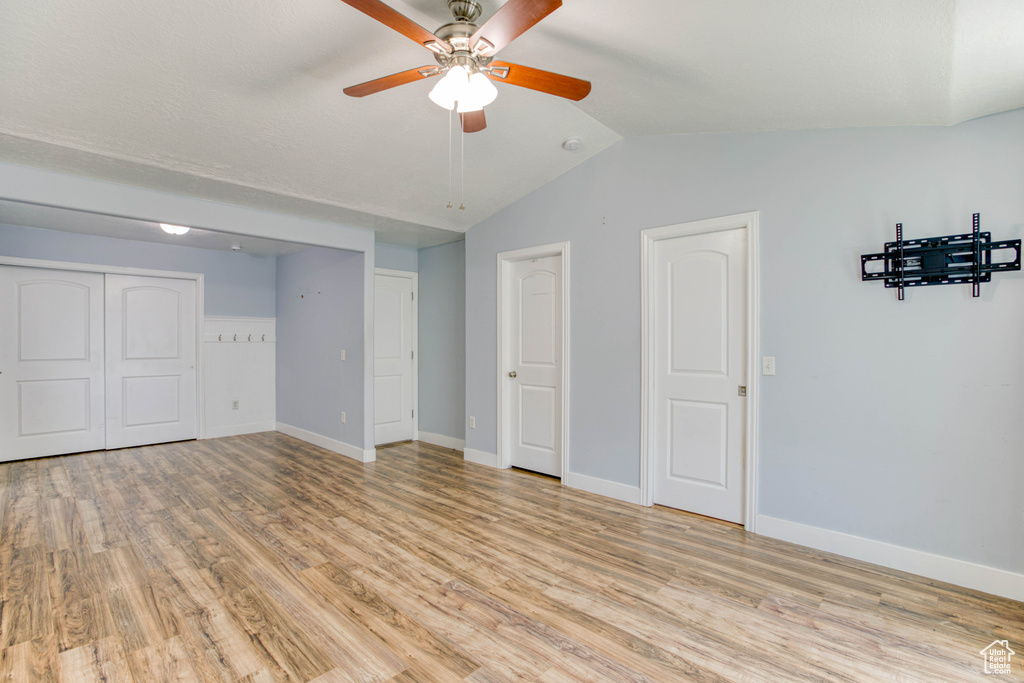 Unfurnished bedroom featuring light wood-style floors, vaulted ceiling, baseboards, and a ceiling fan