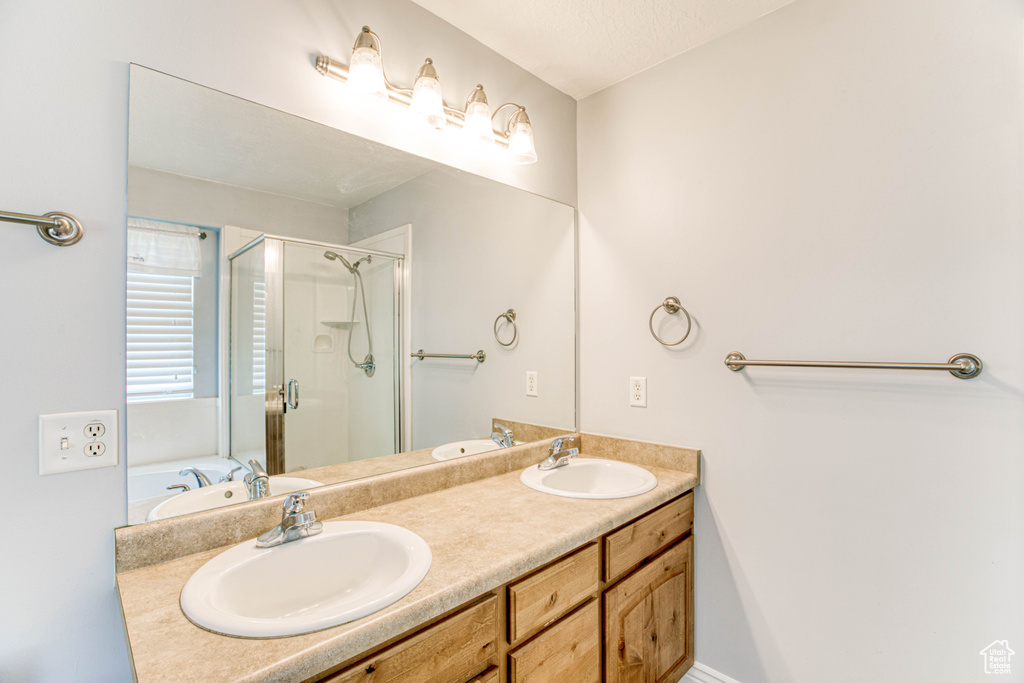 Bathroom with a stall shower, double vanity, and a tub