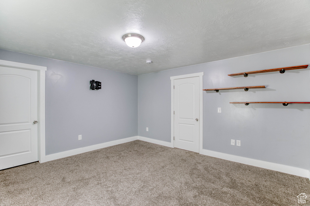 Carpeted spare room featuring baseboards and a textured ceiling