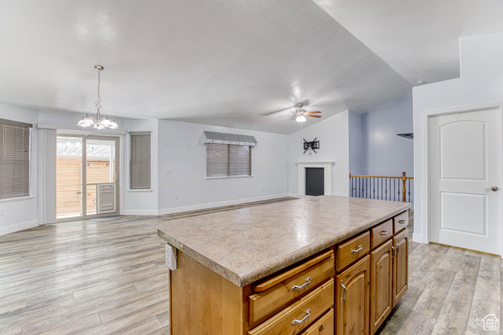 Kitchen with a ceiling fan, light wood-style floors, a chandelier, vaulted ceiling, and open floor plan