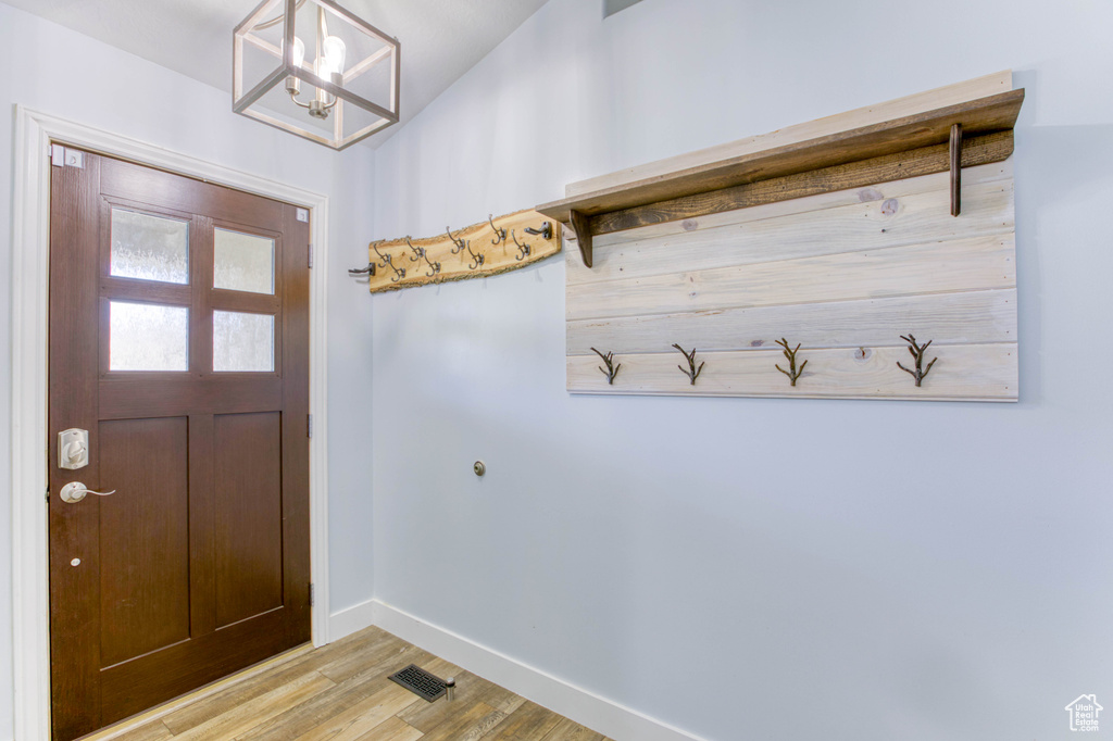 Mudroom with light wood-type flooring, baseboards, and a chandelier