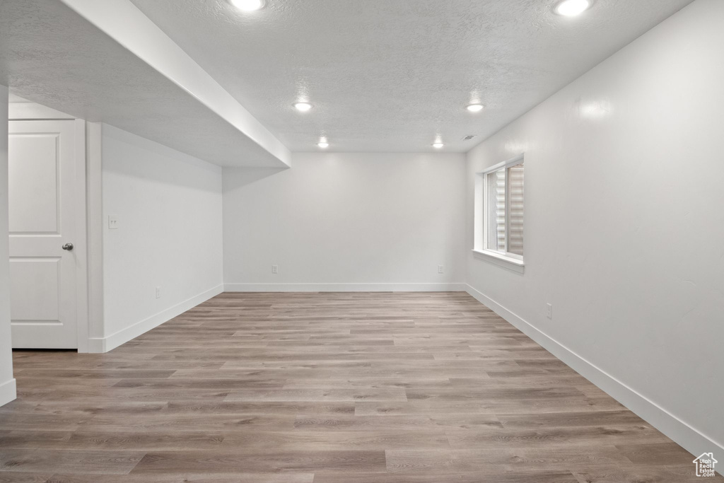 Basement featuring a textured ceiling, recessed lighting, baseboards, and light wood-type flooring