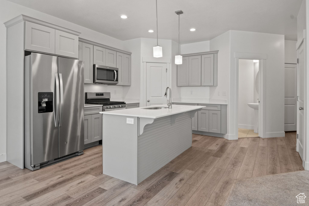 Kitchen featuring appliances with stainless steel finishes, gray cabinets, a sink, light wood-style floors, and recessed lighting