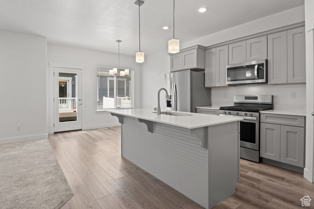 Kitchen with appliances with stainless steel finishes, gray cabinetry, a sink, recessed lighting, and a chandelier