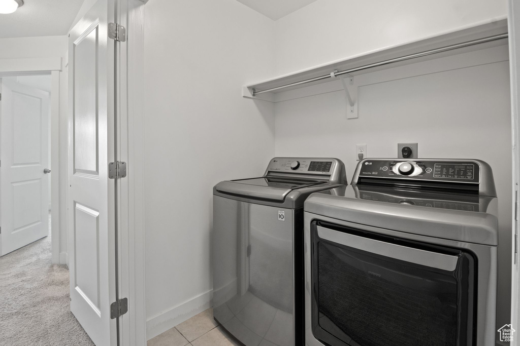 Laundry area with washer and clothes dryer, baseboards, and light tile patterned flooring