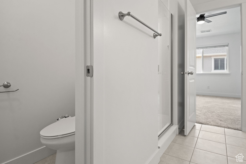 Full bathroom featuring tile patterned flooring, toilet, baseboards, and a shower stall