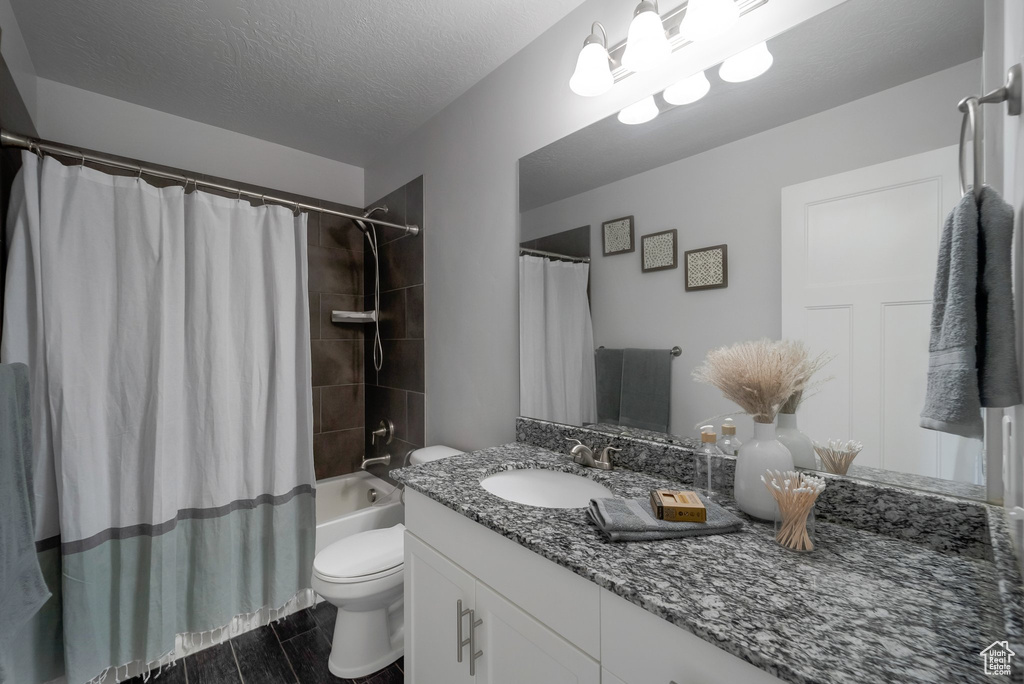 Full bath featuring vanity, toilet, shower / bath combo, a textured ceiling, and wood finished floors