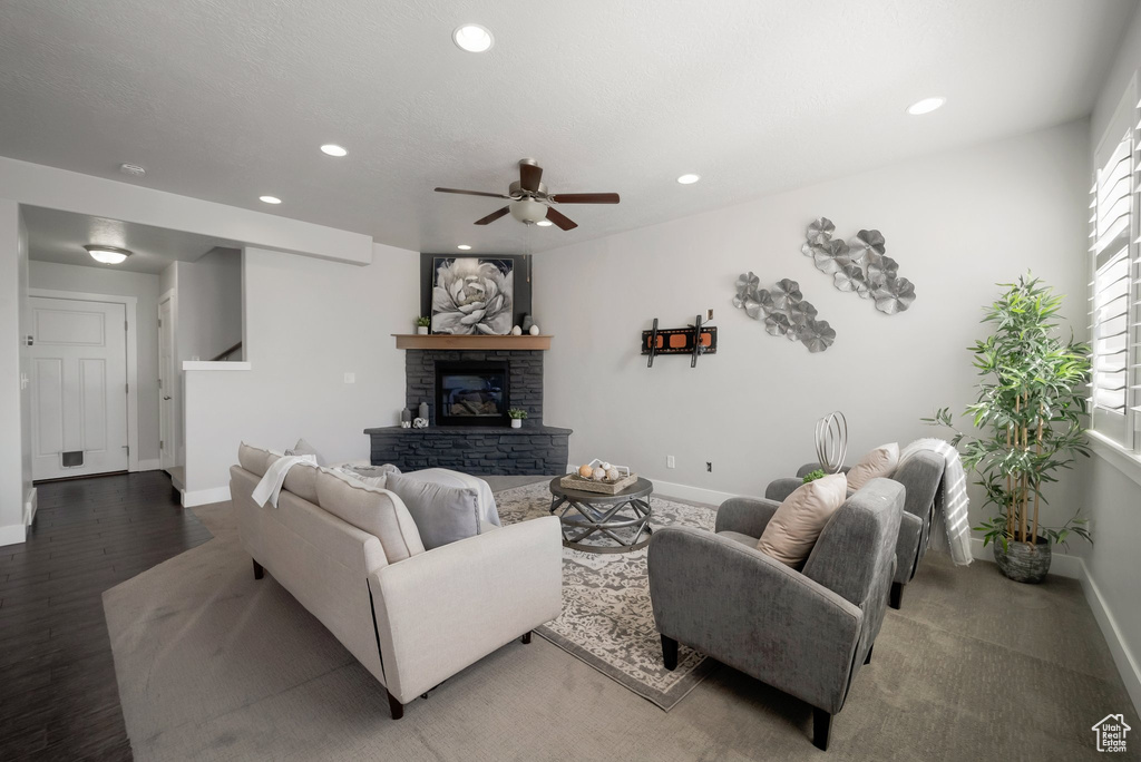 Living room featuring baseboards, ceiling fan, recessed lighting, a fireplace, and wood finished floors