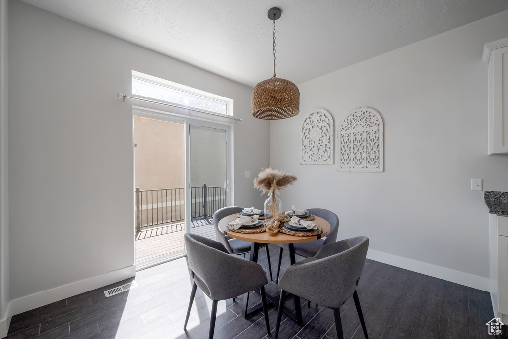 Dining space with dark wood-style flooring and baseboards