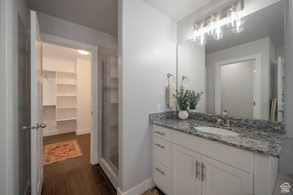 Full bathroom featuring vanity, a shower stall, a walk in closet, and baseboards