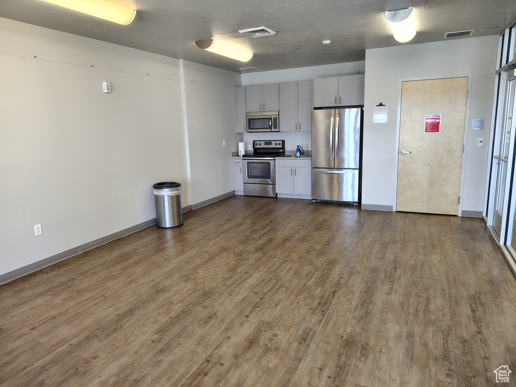 Kitchen with stainless steel appliances, wood finished floors, baseboards, and light countertops