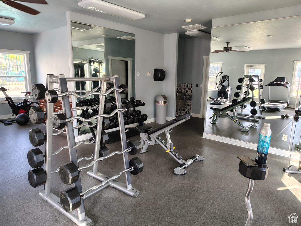 Gym with ceiling fan and baseboards