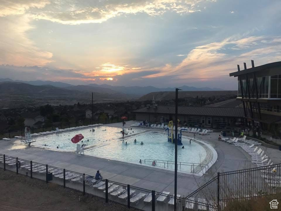 Pool at dusk featuring a mountain view and a community pool