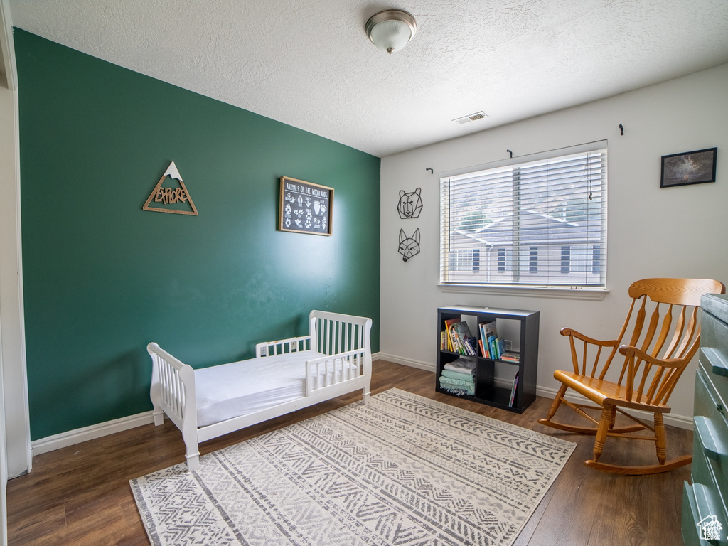 Bedroom with wood finished floors, a textured ceiling, and baseboards