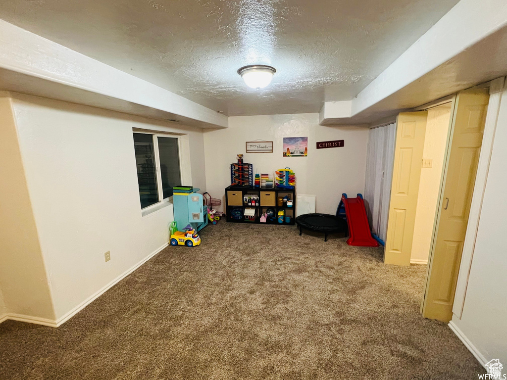 Rec room with carpet, a textured ceiling, and baseboards