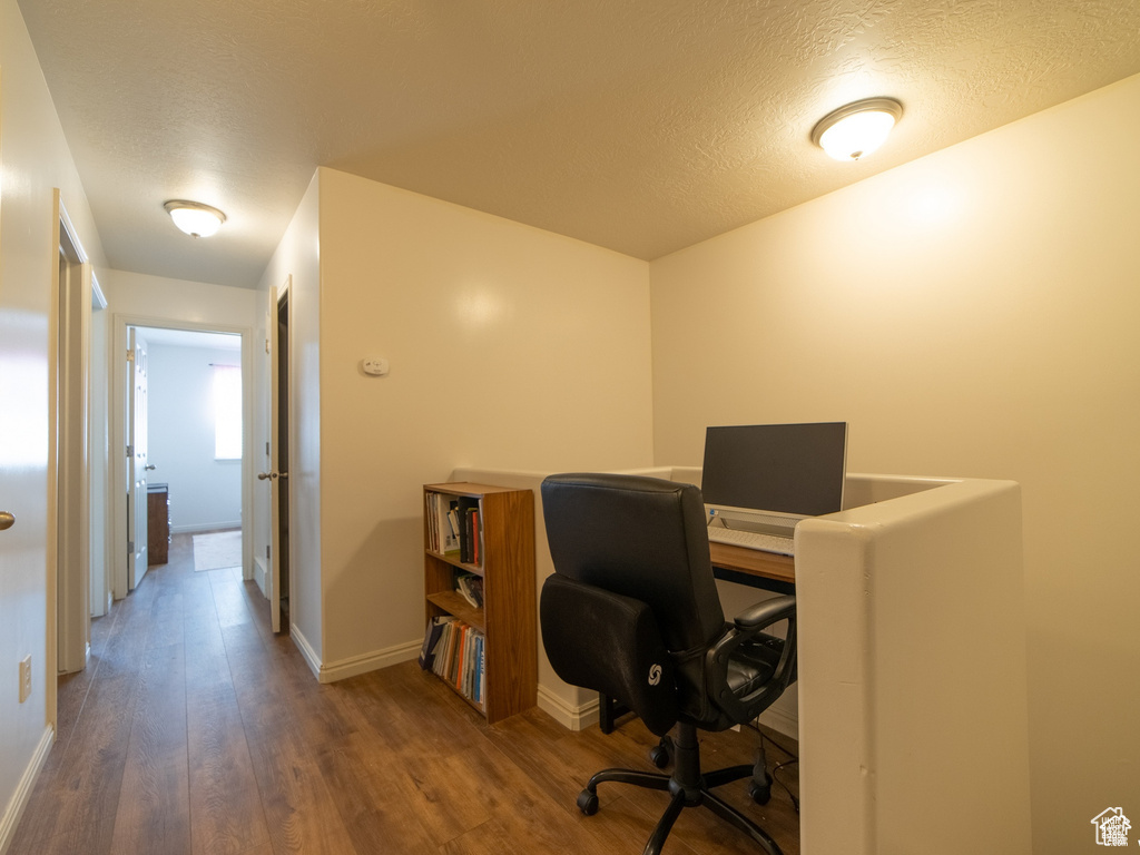 Office space featuring a textured ceiling, wood finished floors, and baseboards