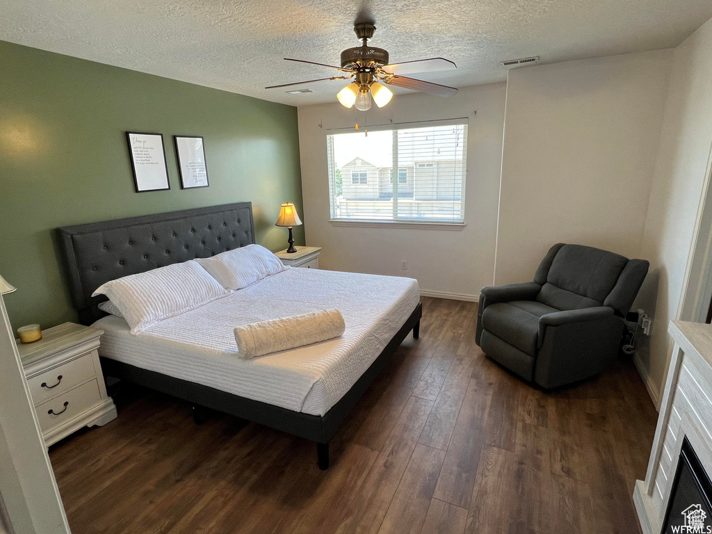 Bedroom featuring dark wood-style flooring, a textured ceiling, a ceiling fan, and baseboards