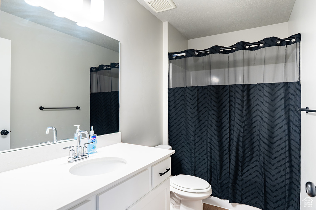 Bathroom featuring vanity, toilet, and a shower with curtain