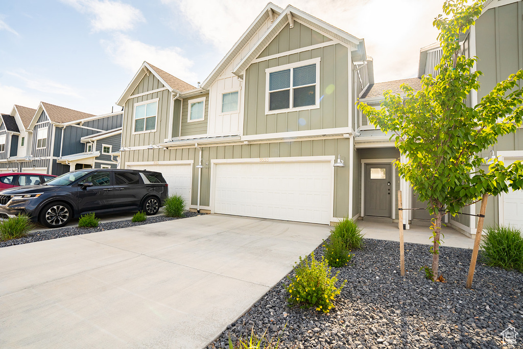 View of property featuring board and batten siding, a garage, and concrete driveway