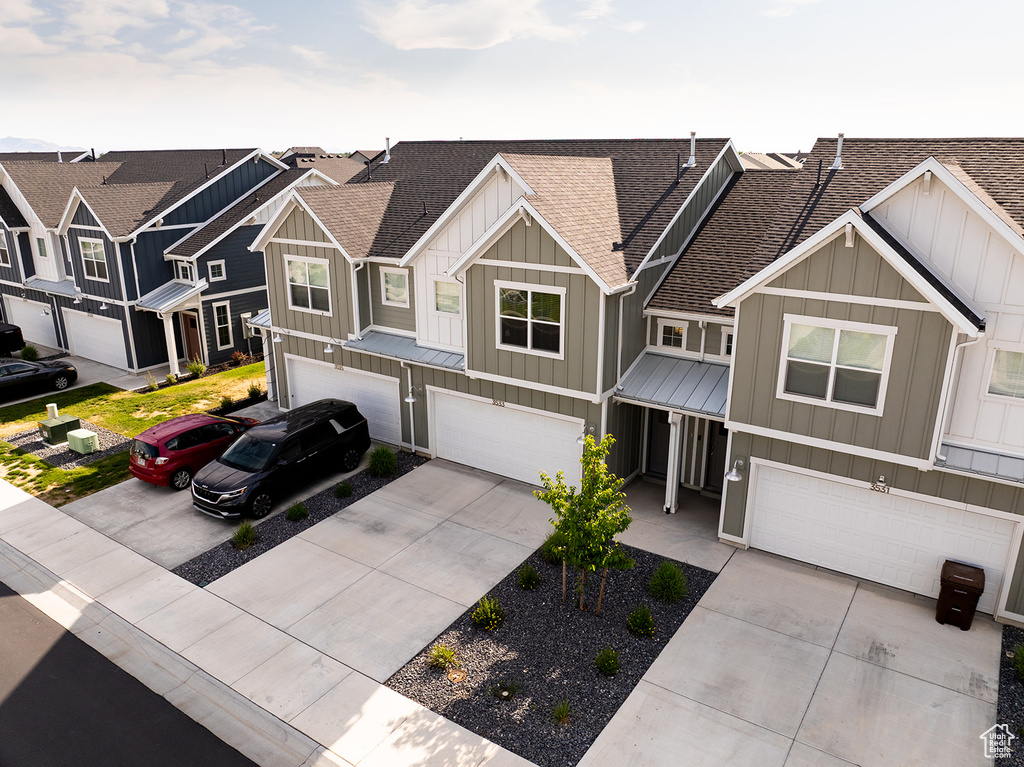 View of front of house with roof with shingles, board and batten siding, an attached garage, and concrete driveway