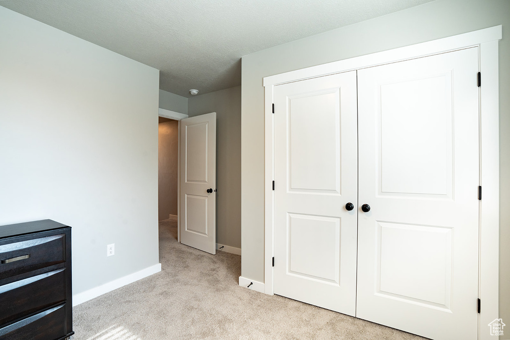 Unfurnished bedroom featuring carpet floors, baseboards, and a closet