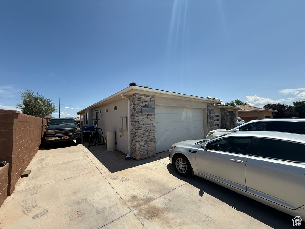 View of side of property featuring stone siding, a garage, stucco siding, and concrete driveway