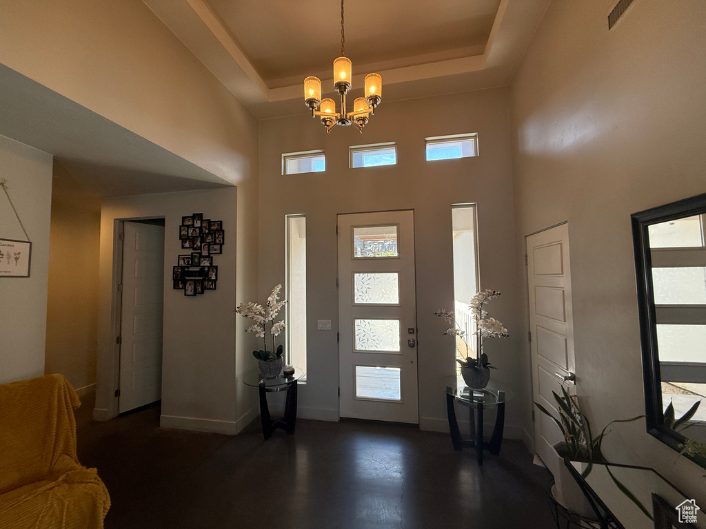 Foyer entrance featuring a chandelier, baseboards, a high ceiling, and a tray ceiling