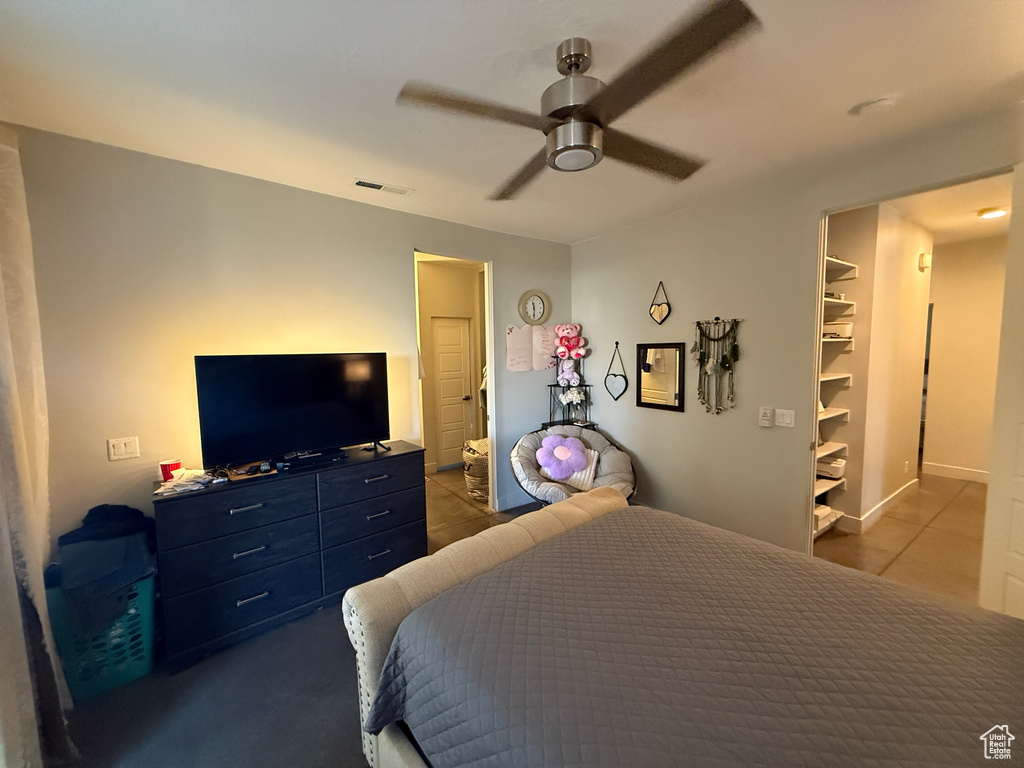 Bedroom with tile patterned flooring, a ceiling fan, and a spacious closet
