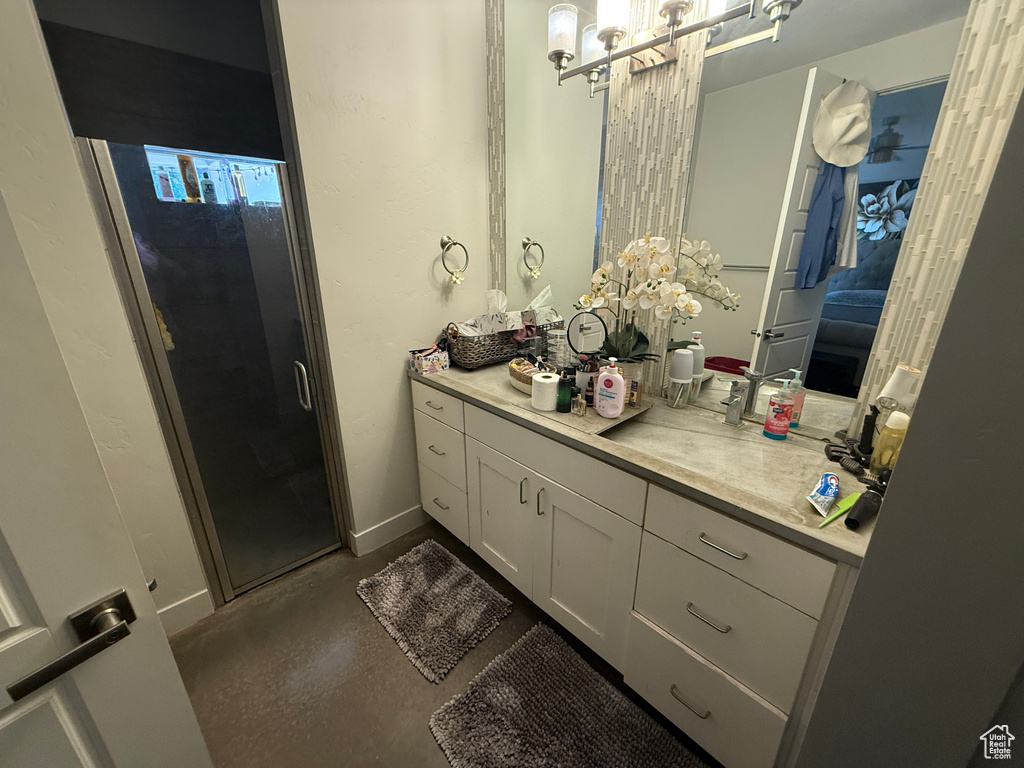 Bathroom featuring vanity, a shower stall, concrete flooring, and baseboards