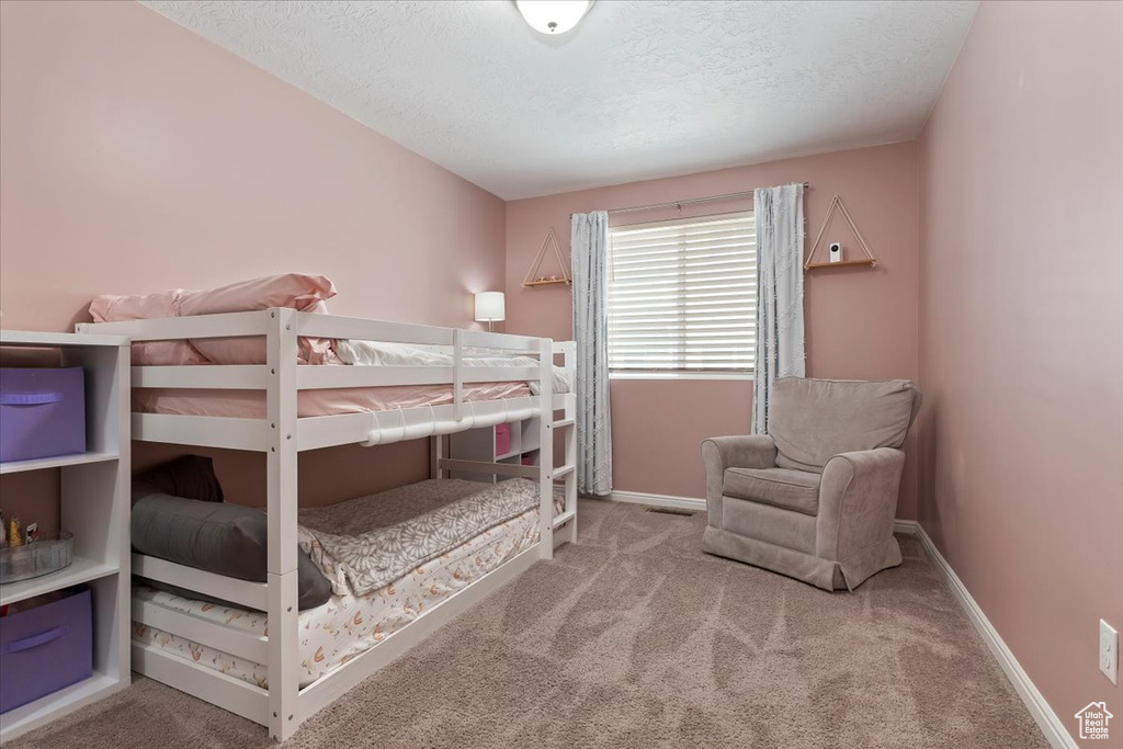 Carpeted bedroom with a textured ceiling and baseboards