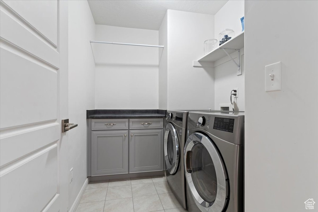 Laundry room featuring independent washer and dryer, cabinet space, and light tile patterned floors
