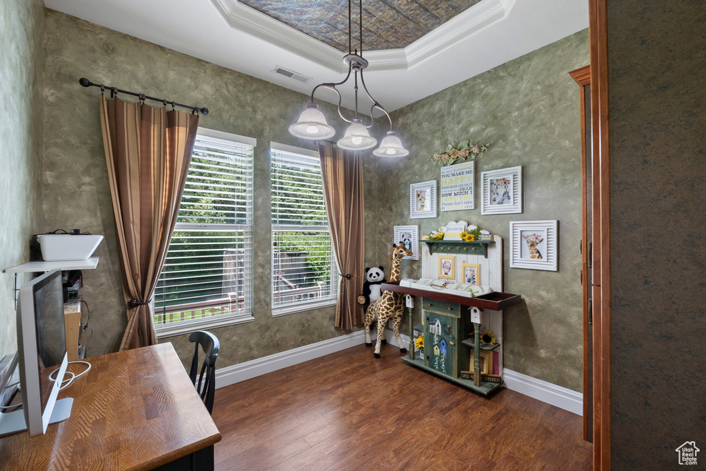 Office area featuring wood finished floors, crown molding, baseboards, and a tray ceiling