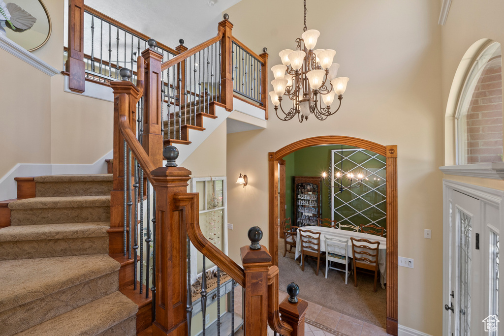 Entryway with a high ceiling, carpet floors, a chandelier, stairway, and baseboards