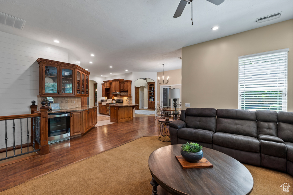Carpeted living area featuring arched walkways, wine cooler, a ceiling fan, recessed lighting, and wood finished floors