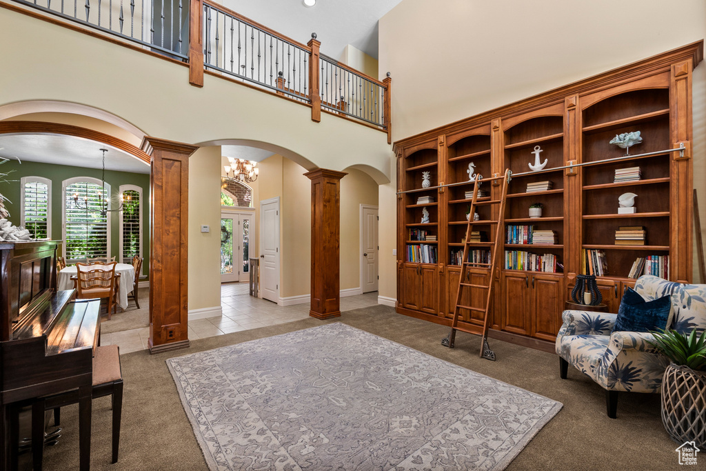 Sitting room with arched walkways, ornate columns, a towering ceiling, and carpet floors