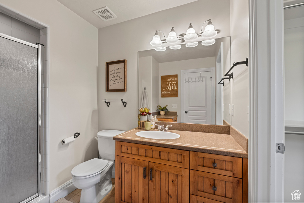 Bathroom featuring vanity, a stall shower, toilet, and tile patterned floors
