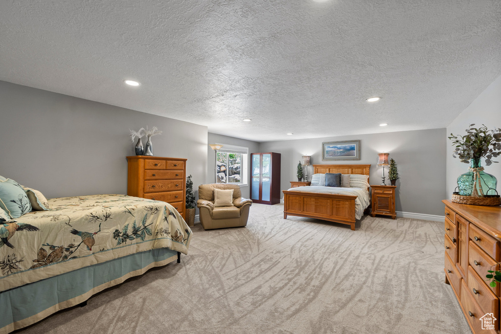 Bedroom with a textured ceiling, light carpet, recessed lighting, and baseboards