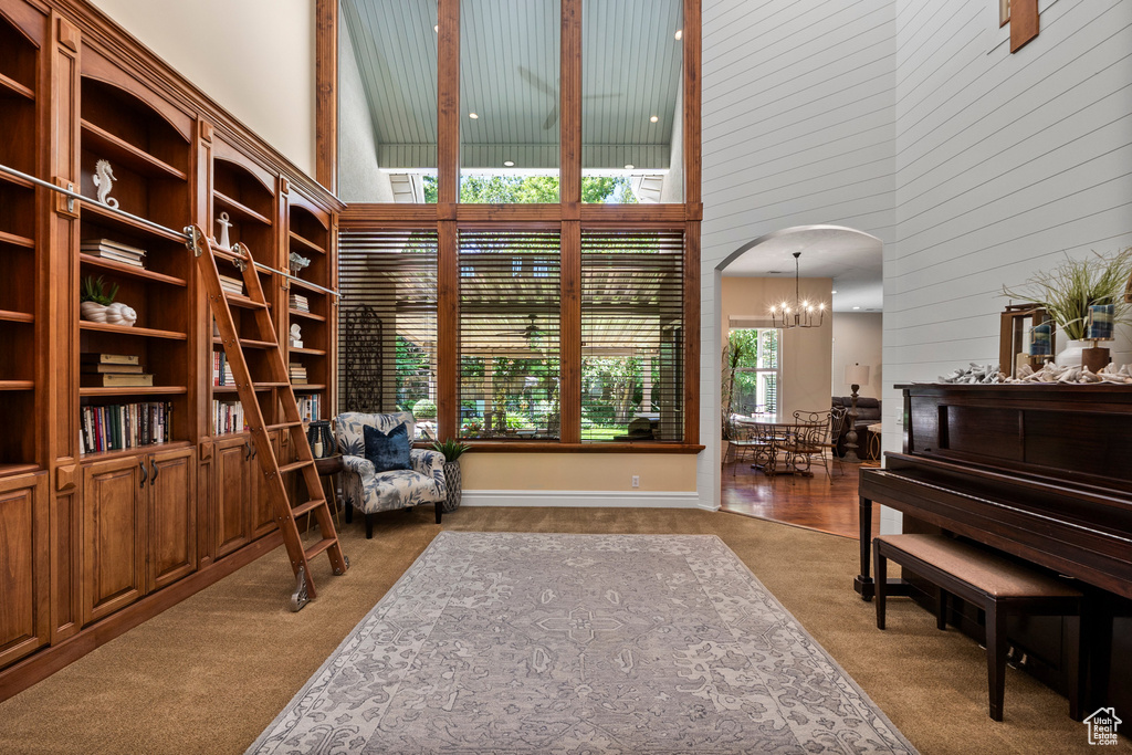 Living area with a high ceiling, carpet flooring, a chandelier, arched walkways, and wood walls