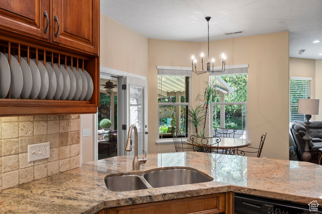 Kitchen featuring a sink, light stone counters, black dishwasher, and brown cabinets