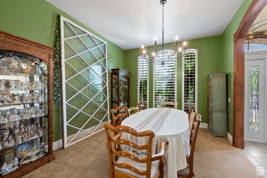 Dining area featuring light carpet, a chandelier, and baseboards