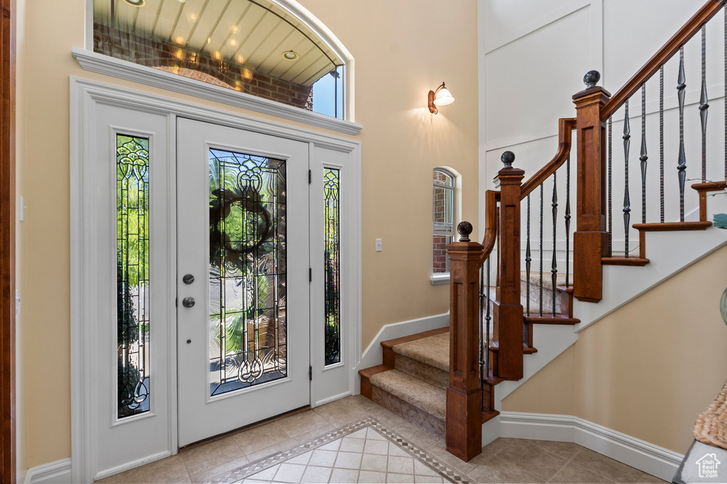 Foyer with tile patterned floors, stairway, baseboards, and a towering ceiling