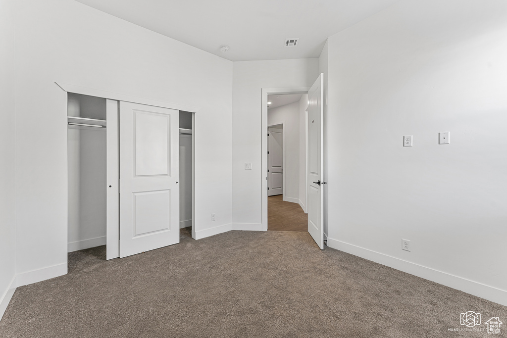Unfurnished bedroom featuring carpet floors, baseboards, and a closet