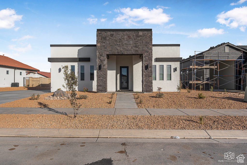 Contemporary home with stone siding, stucco siding, and central AC unit