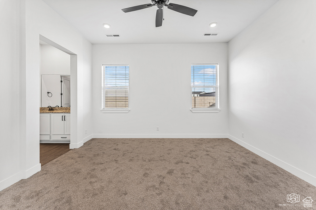 Unfurnished bedroom featuring carpet floors, baseboards, ensuite bath, and a ceiling fan