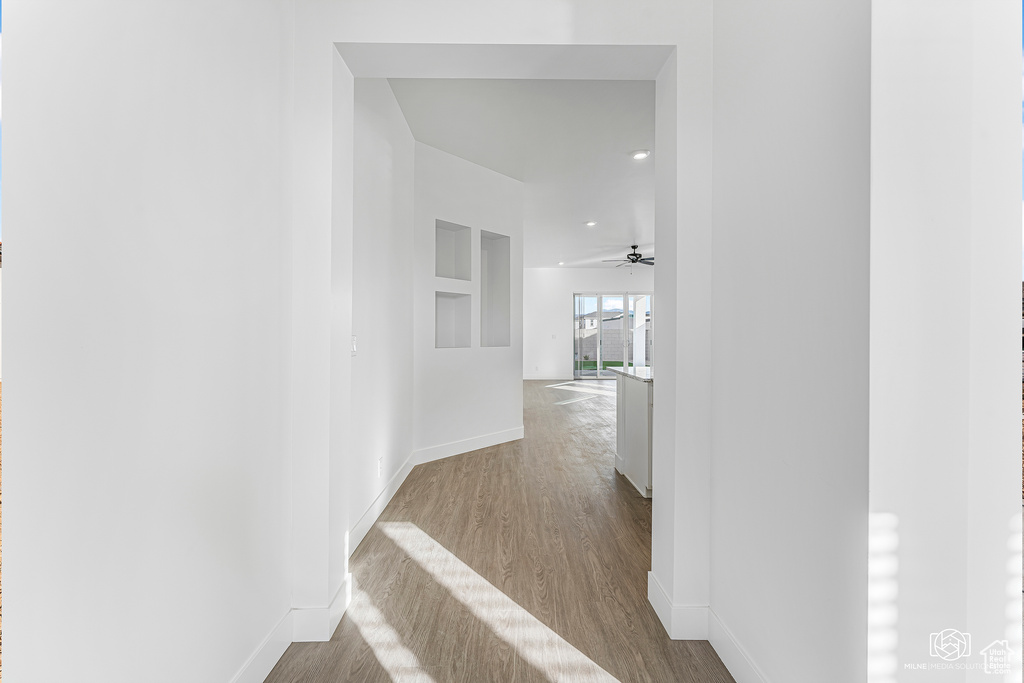 Hall featuring baseboards, wood finished floors, and recessed lighting