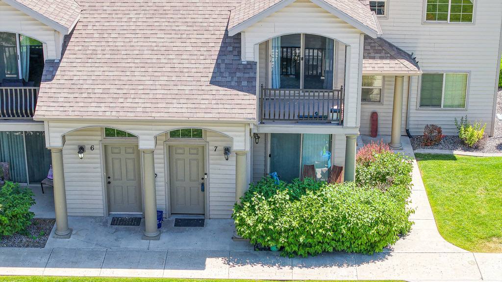 Doorway to property with a shingled roof and a balcony
