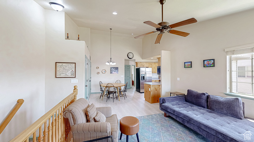 Living room featuring light wood-style floors, a ceiling fan, high vaulted ceiling, and recessed lighting